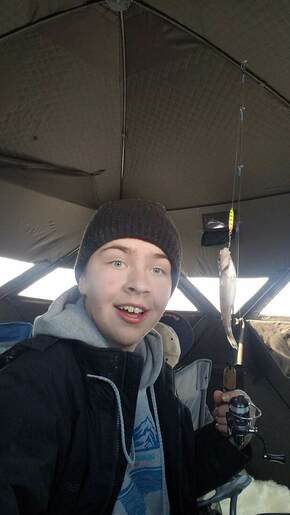 Me with a freshly caught fish inside of a ice fishing tent